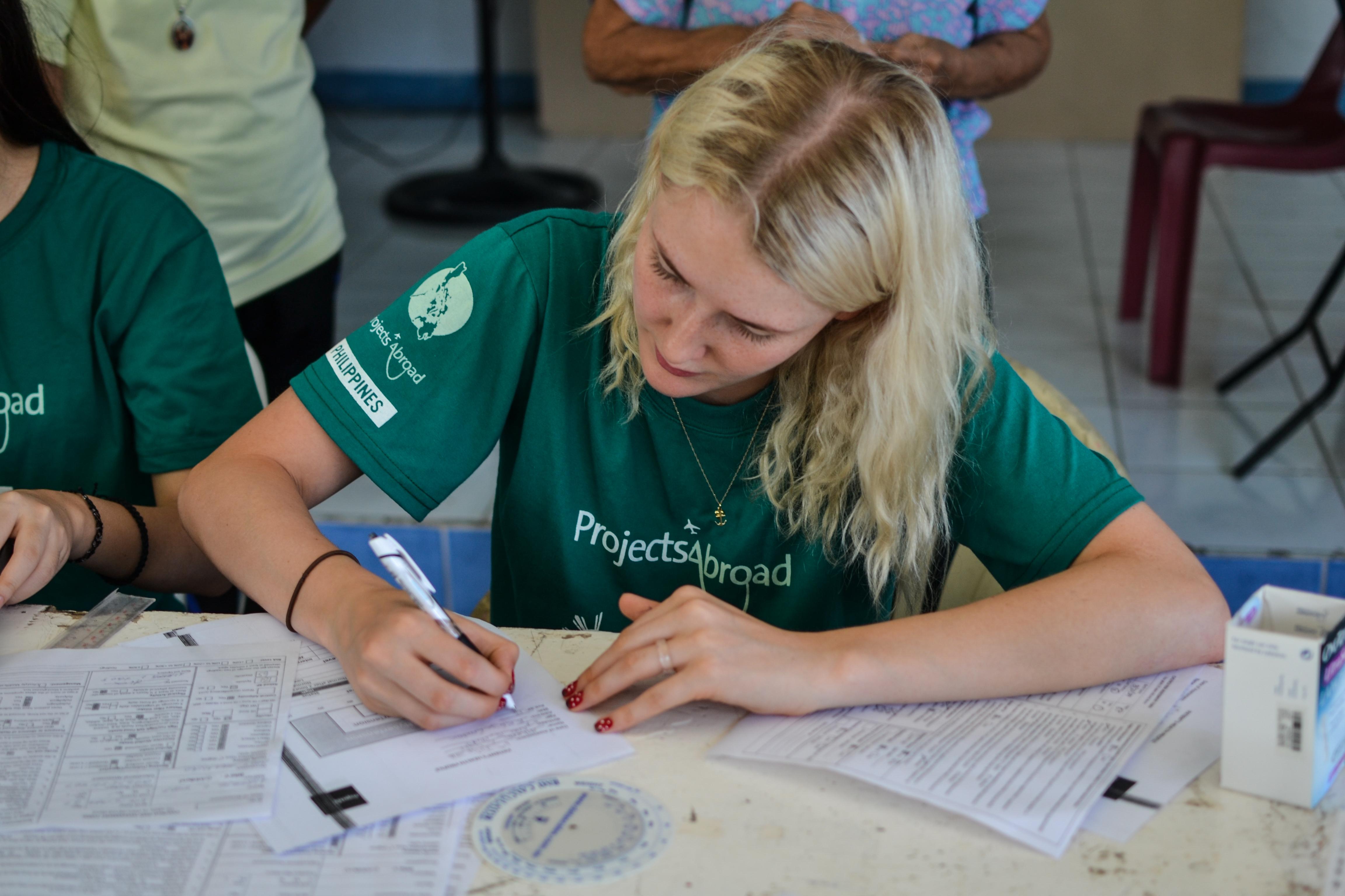 A Projects Abroad student at her Physiotherapy placement for teenagers in the Philippines, takes notes during an outreach. During an outreach, a student on the Physiotherapy internship for teenagers in the Philippines, takes notes.